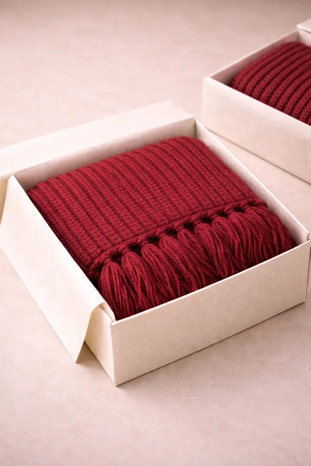 Red knitted scarf in a white box on a beige background