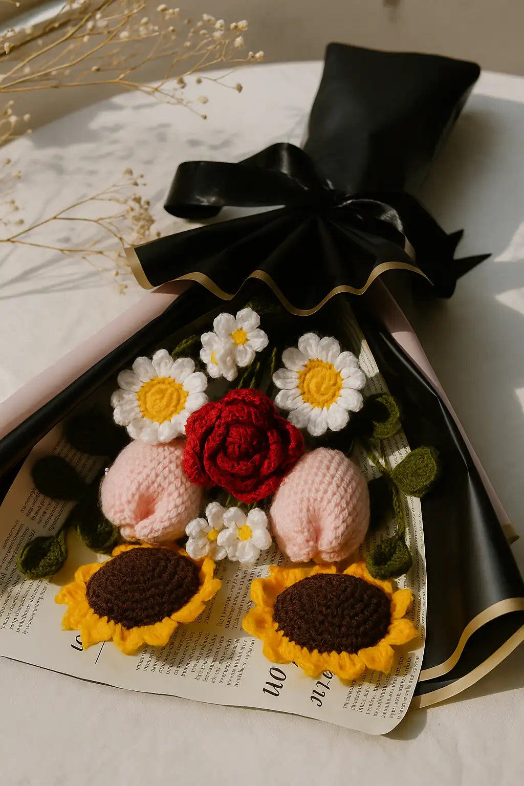 Knitted flowers and roses with a black ribbon on a newspaper background